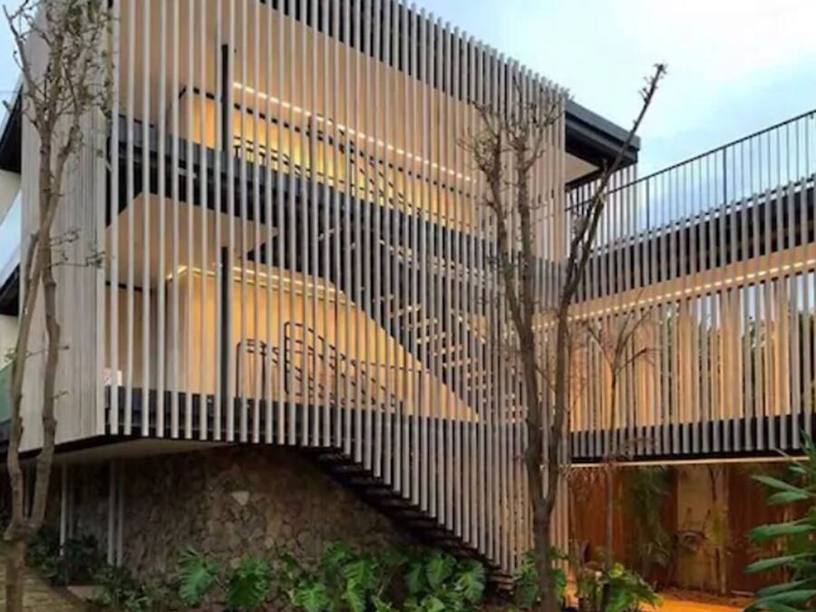 A modern building with a unique vertical wooden facade, a stone base, and a staircase leading to an upper level.