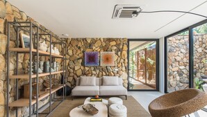 Una sala de estar moderna con pared de piedra, un sofá, una mesa de centro y una zona de estar original.
