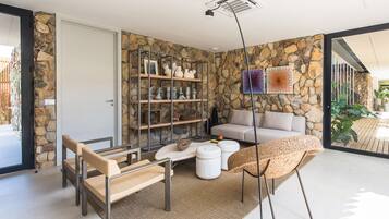 A modern living room with stone walls, a sofa, a coffee table, and wicker furniture.