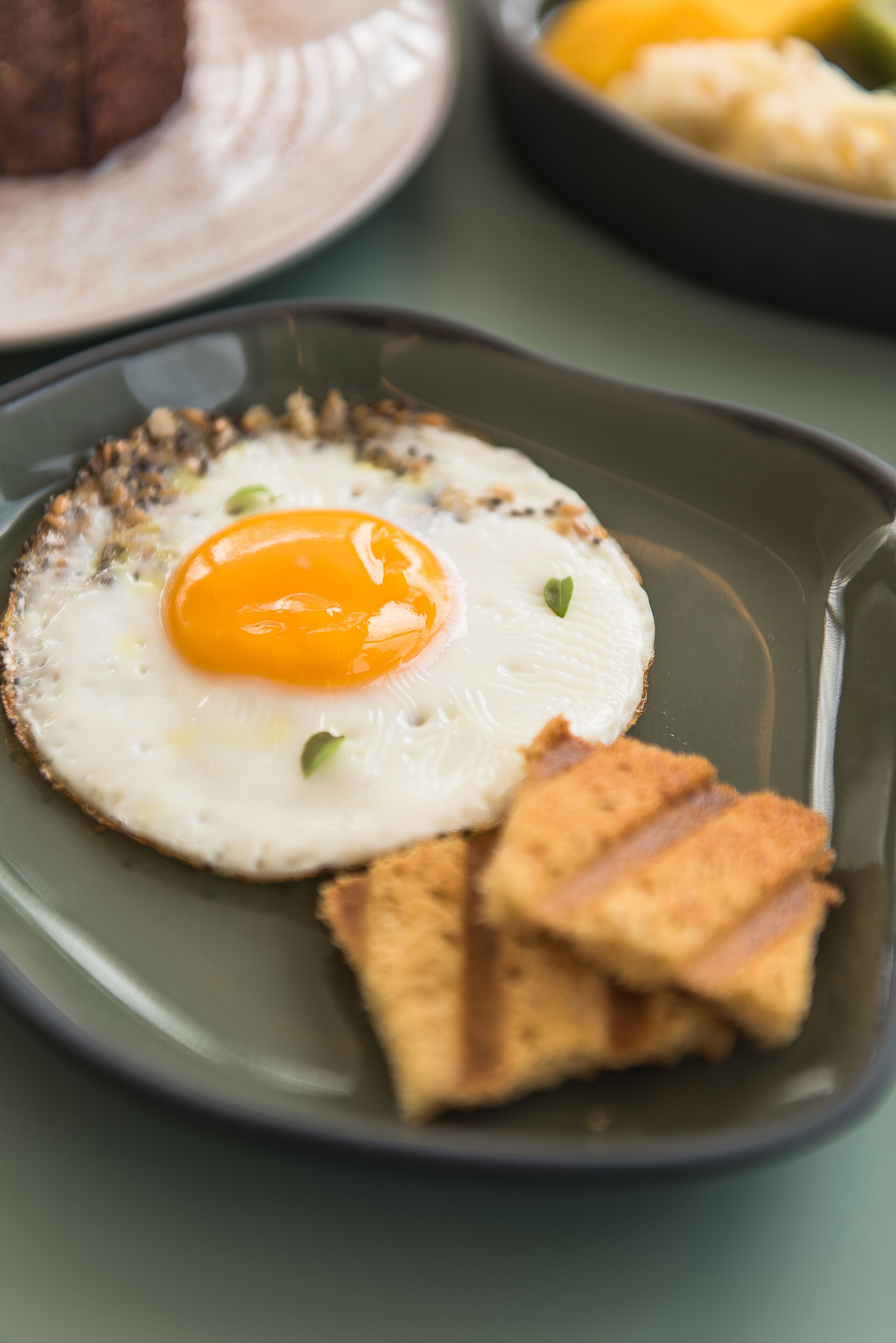 Une assiette avec un œuf au plat, des toasts et une petite portion de légumes.