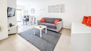 Ein modernes Wohnzimmer mit einem grauen Sofa, einem kleinen weißen Tisch und einem grauen Teppich.