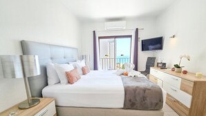 Ein modernes Hotelzimmer mit einem großen Bett, einem Schreibtisch, einem Fernseher und einem Balkon mit Blick.
