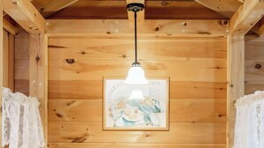 A wooden dining area with a table set for two, a hanging light fixture, and a framed picture on the wall. - Amazing Views! Hot Tub,Pool Table,Fireplace,Relax! (Gatlinburg)