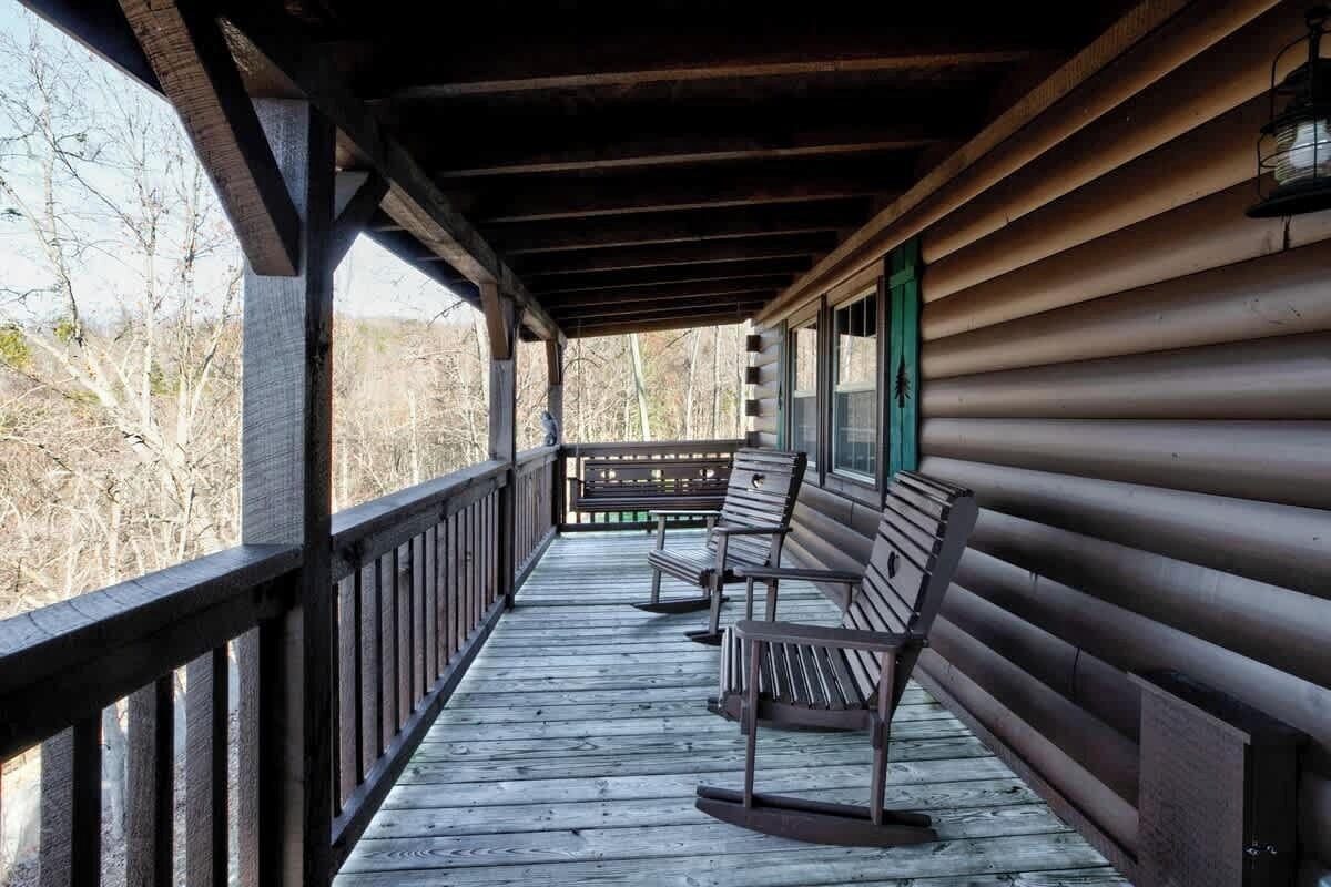A wooden porch with benches and a railing, overlooking a natural landscape.
