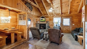 A cozy cabin interior with a stone fireplace, wooden furniture, and a television. - Amazing Views! Hot Tub,Pool Table,Fireplace,Relax! (Gatlinburg)
