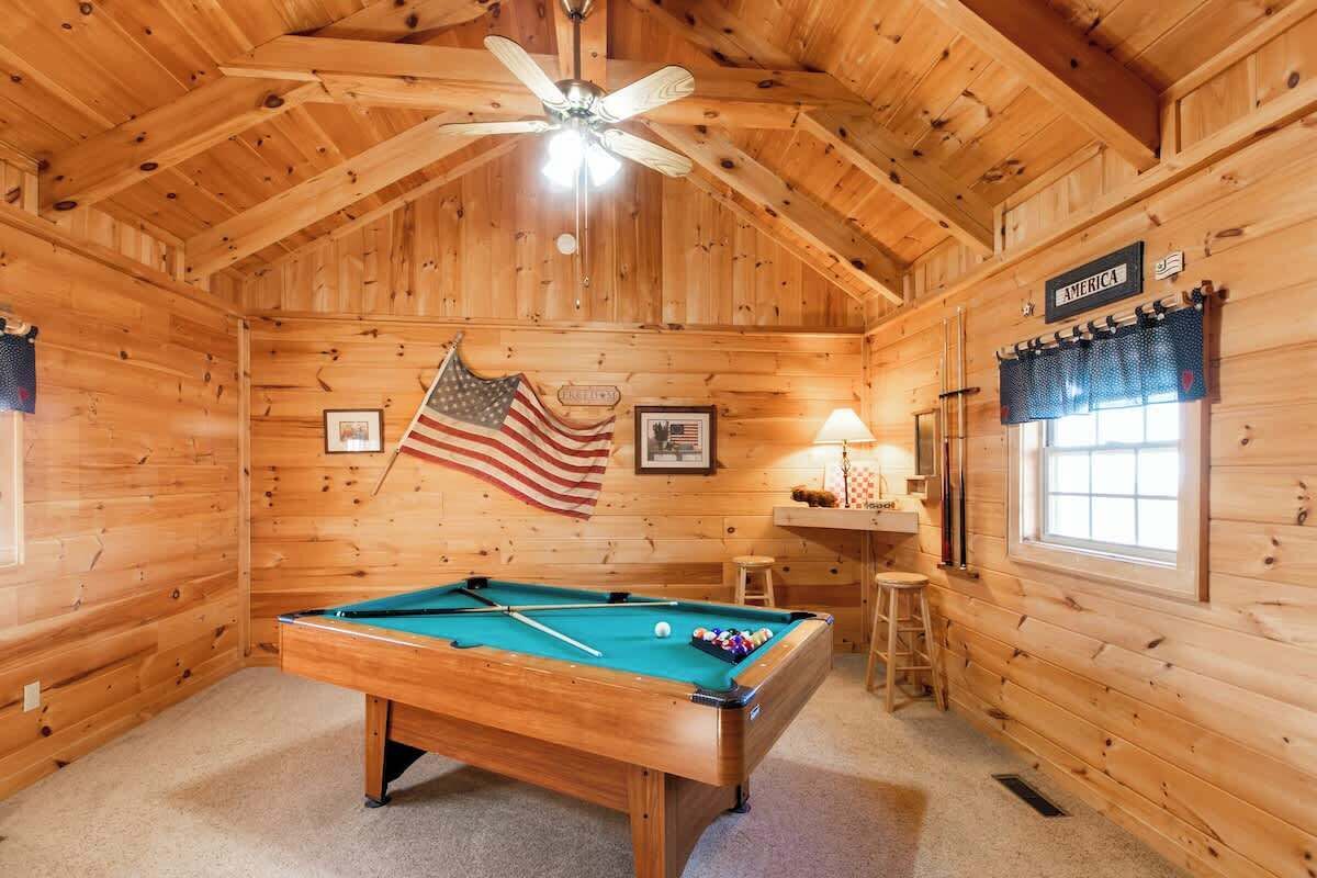Une cabane en bois avec une table de billard, des drapeaux américains et une pancarte portant l’inscription « AMERICA ».