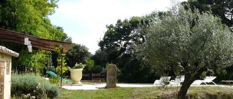 A garden with a pergola, a large planter, and a stone structure.