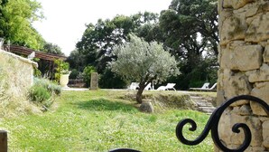 A garden with a stone wall, a pergola, and a tree with white blossoms.