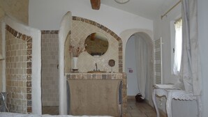 A bedroom with a large bed, a vanity with a mirror, and a brick-patterned wall.