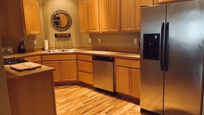 A kitchen with wooden cabinets, a stainless steel refrigerator, a dishwasher, and a wooden countertop.