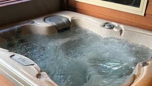 A hot tub with a control panel, surrounded by wooden decking.
