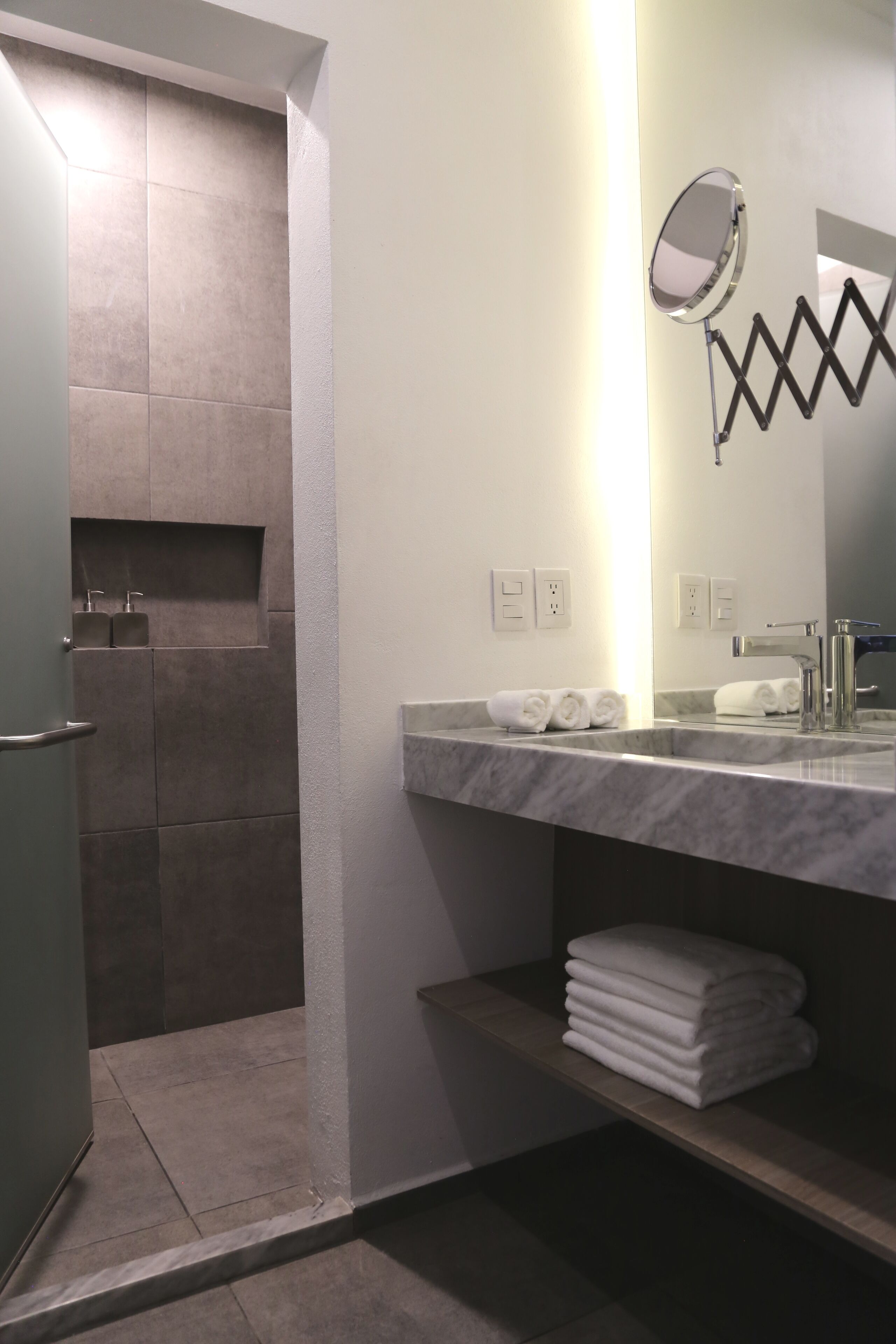 A bathroom with a shower, a sink with a mirror, and a towel rack.
