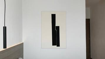 Un dormitorio minimalista con una cama, una obra de arte abstracta colgada en la pared y un cabecero de madera.