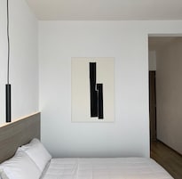 Un dormitorio minimalista con una cama, una obra de arte abstracta colgada en la pared y un cabecero de madera.