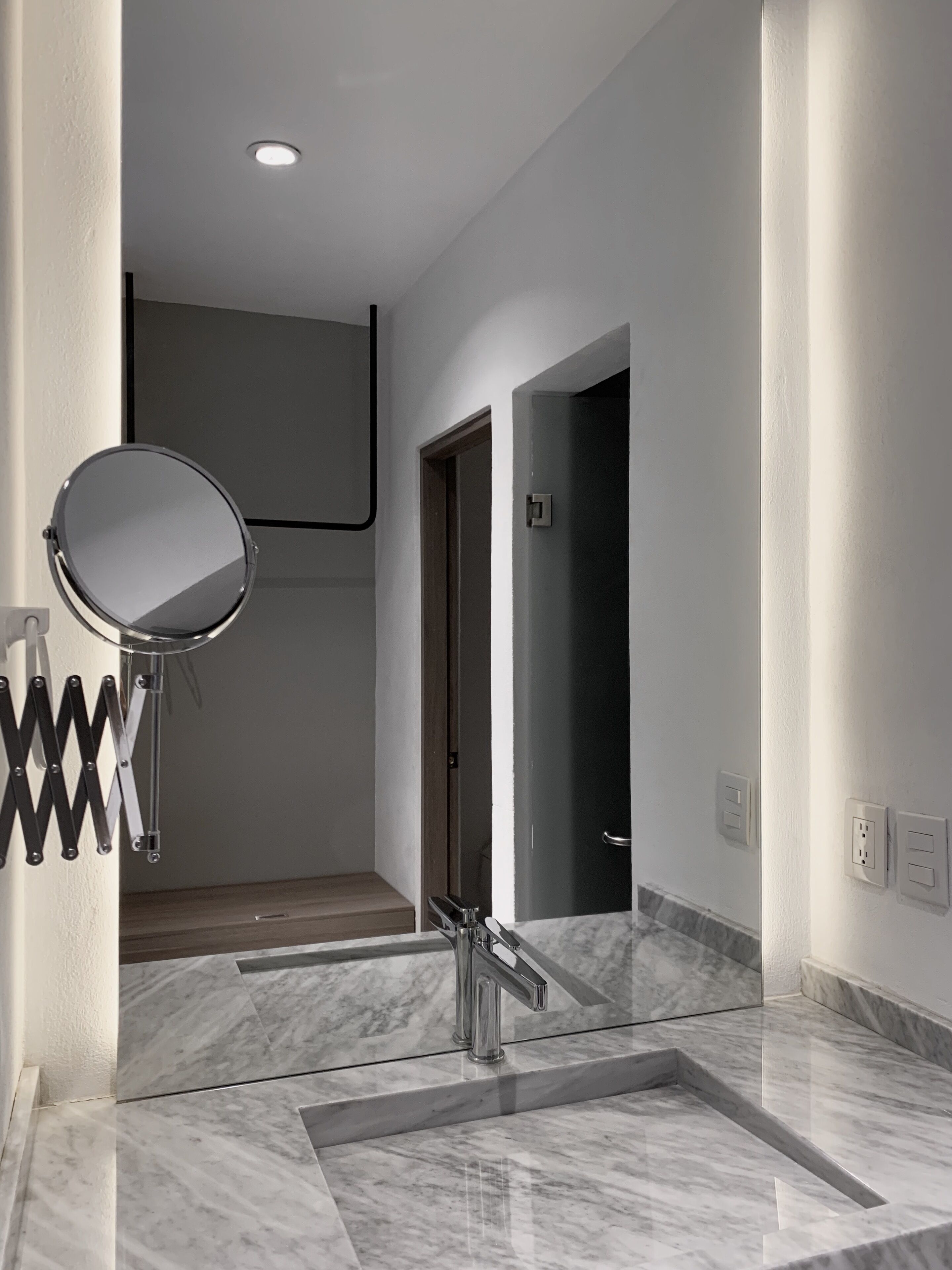 Un baño moderno con un espejo grande, un lavamanos y una zona de ducha.
