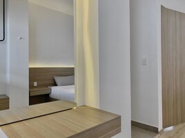 Habitación de hotel con cama, mesita de noche y suelo de madera.