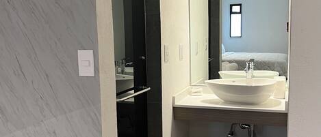 A modern bathroom with a large mirror, a bathtub, and a sink.