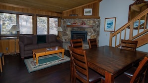 Ein gemütliches Wohnzimmer mit Kamin, Holzmöbeln und einer Treppe.