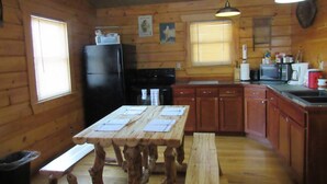 A wooden cabin with a kitchen, dining table, and benches. - Holler Cabin 4 bedroom Hocking Hills-Tar hollow (price calculated per #  guests) (Laurelville)