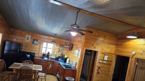 A wooden cabin interior with a kitchen, dining area, and a ceiling fan. - Holler Cabin 4 bedroom Hocking Hills-Tar hollow (price calculated per #  guests) (Laurelville)