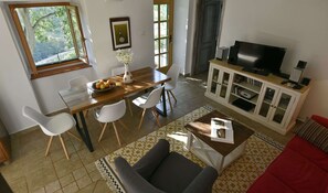 Relax in this open-plan living space with a dining area and seating area, featuring a large window with a view of the surrounding greenery.