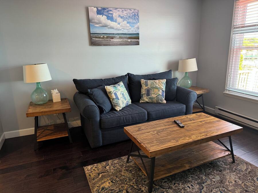 A living room with a dark blue sofa, two matching lamps, a wooden coffee table, and a patterned rug.