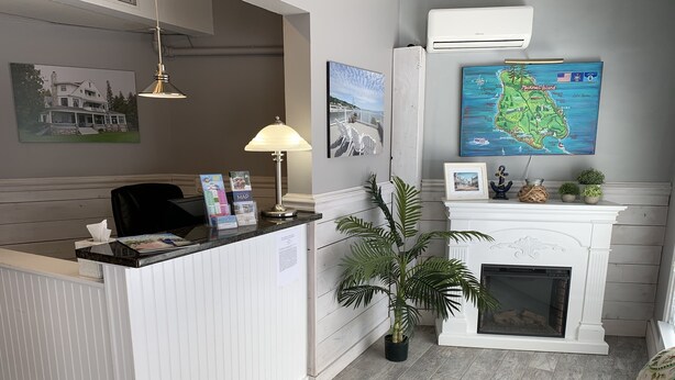 Zona de recepción con un mostrador blanco, un mapa en la pared, una chimenea y una planta en maceta.