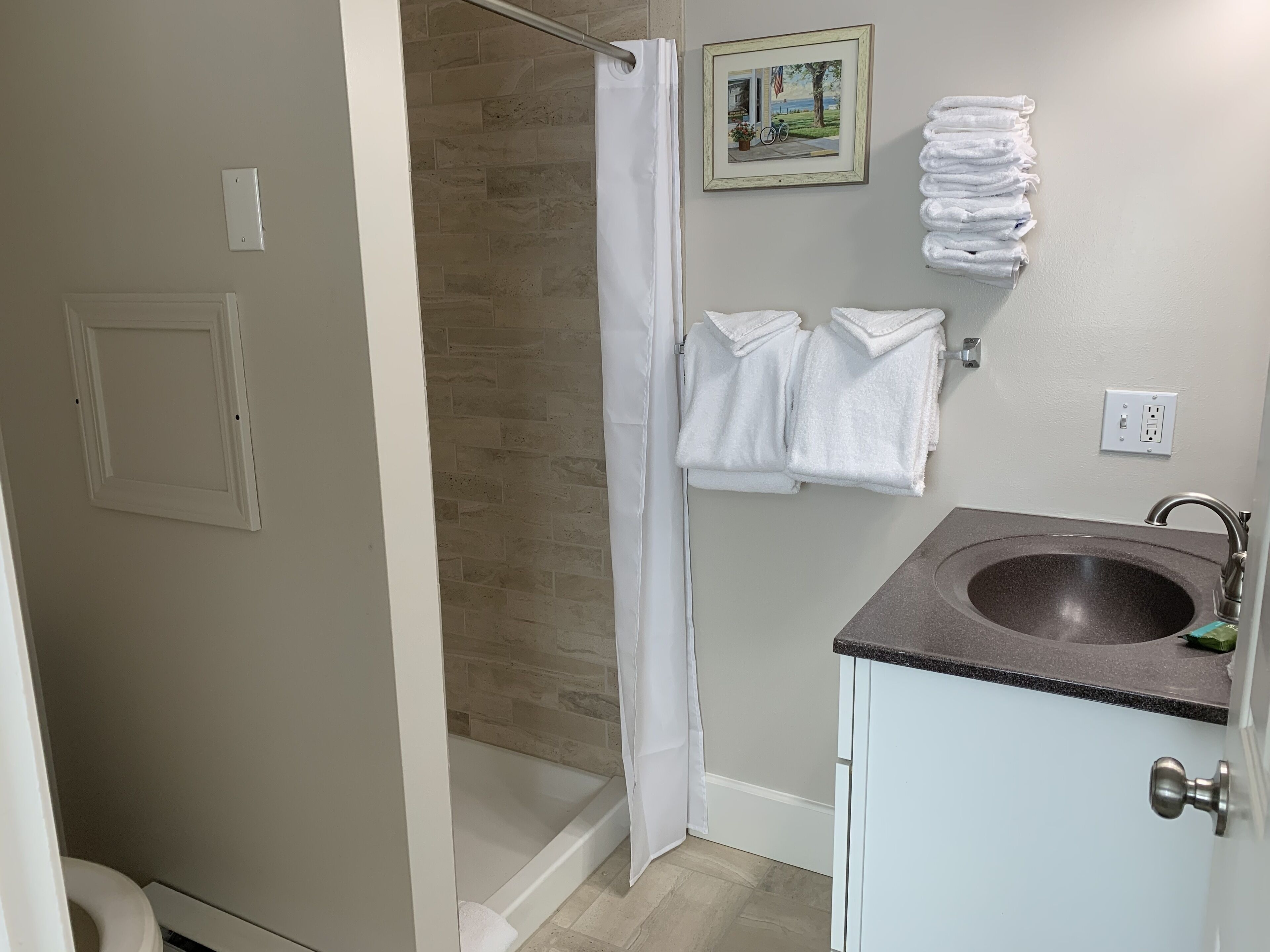 A bathroom with a shower, a sink, and a towel rack.