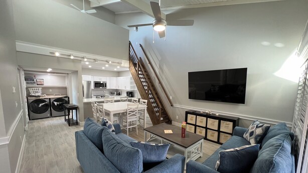 A modern living room with a blue sofa set, a coffee table, and a TV mounted on the wall.