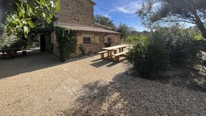 Ein rustikales Steinhaus mit Ziegeldach, einer hölzernen Bank und einem Kieshof.