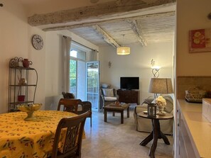 Un salon chaleureux avec une table à manger, des chaises, un téléviseur et un canapé.