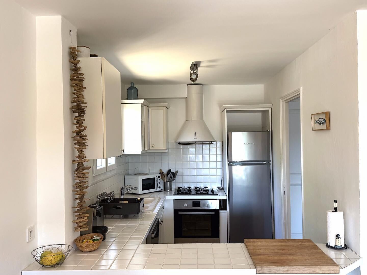 A compact kitchen with white cabinets, a stainless steel refrigerator, a microwave, and a gas stove.