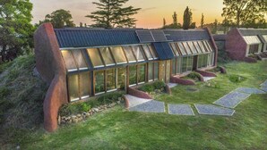 Une maison moderne avec un toit en pente, de grandes fenêtres et un chemin de pierre menant à l’entrée.