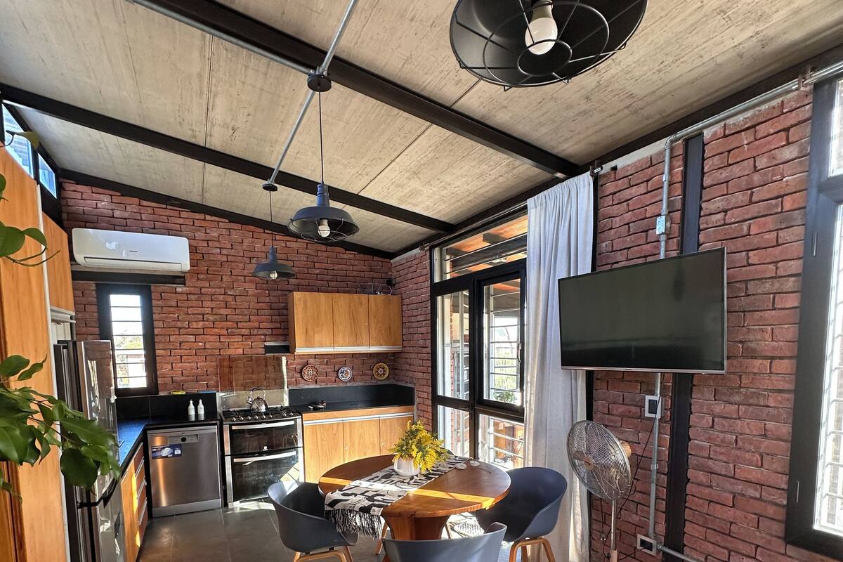A modern kitchen with a brick wall, stainless steel appliances, and a large window.