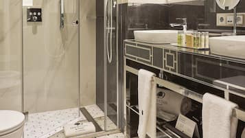 Un baño moderno con ducha acristalada, un espejo grande y un mueble de tocador con lavamanos y toallero.