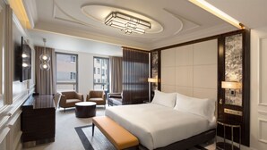 Moderni hotellihuone, jossa on suuri sänky, työpöytä, sohva ja tuoli.
