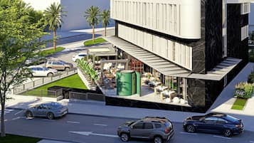 Un bâtiment moderne doté d’un patio sur le toit, d’un espace extérieur aménagé pour s’asseoir et d’un escalier menant à l’entrée.