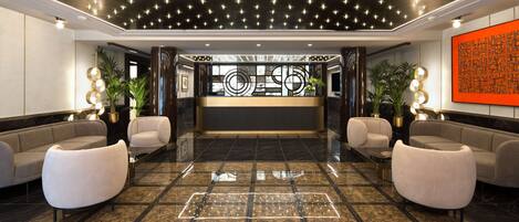 A modern lobby with a reception desk, two sofas, and a decorative wall.