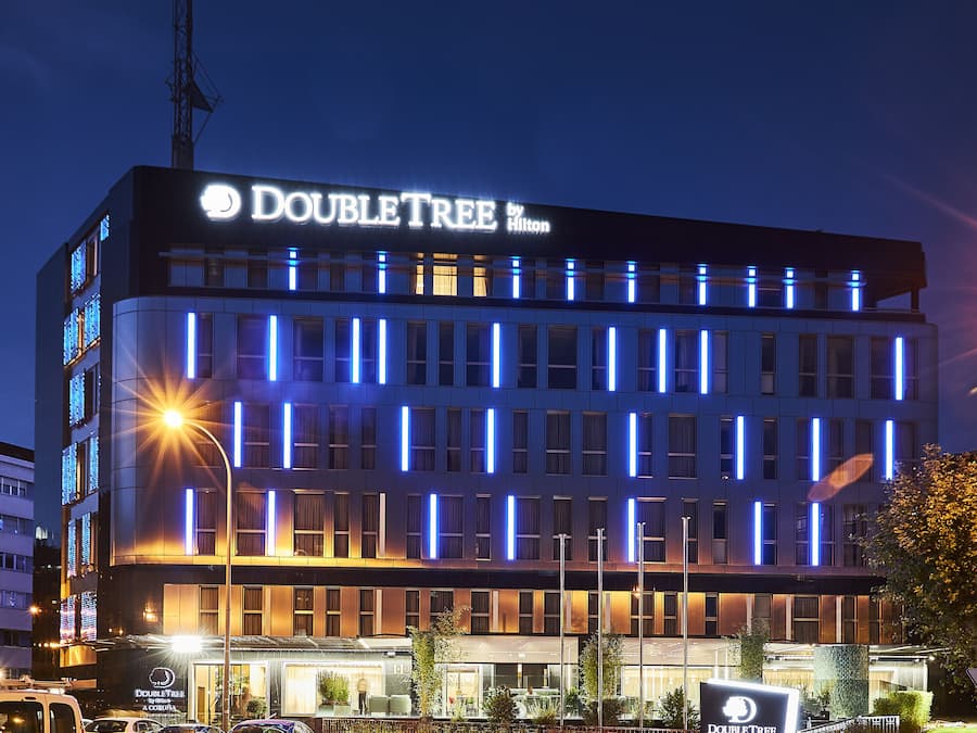 Un hotel DoubleTree by Hilton con fachada moderna, señalización iluminada y entrada visible.