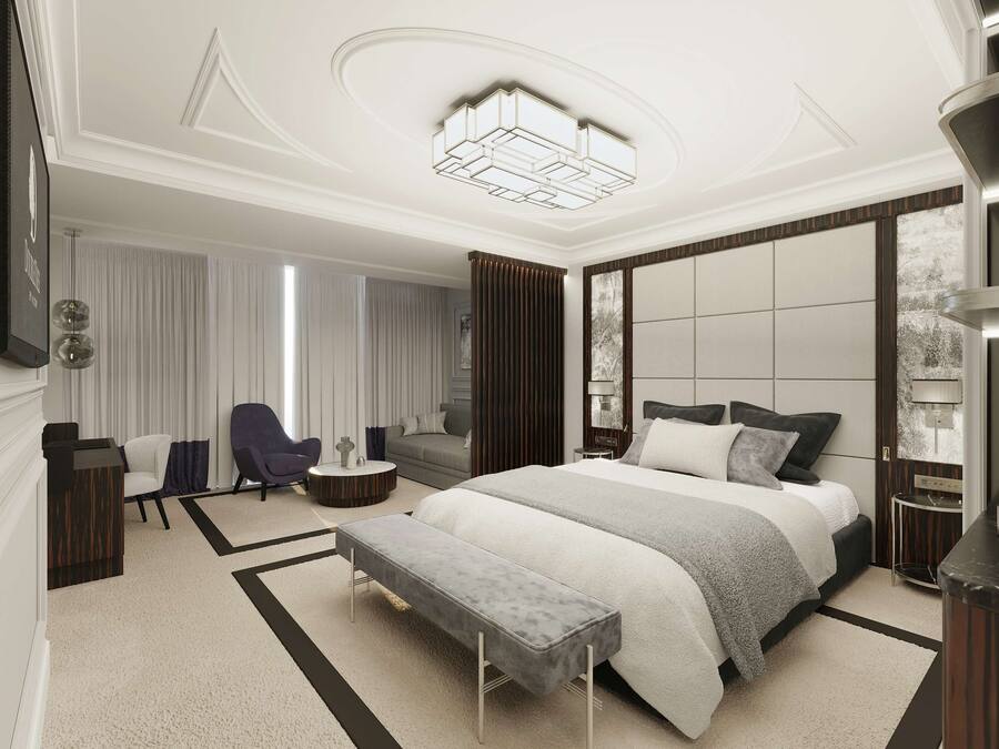 A modern hotel room with a large bed, a seating area with a sofa and armchairs, a coffee machine, and a large window with curtains.