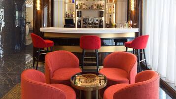A bar area with a curved counter, red upholstered chairs, and a patterned floor.