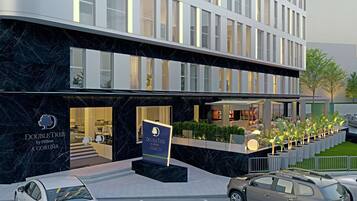 A modern hotel with a marble facade, a visible entrance, and a landscaped outdoor area with seating.