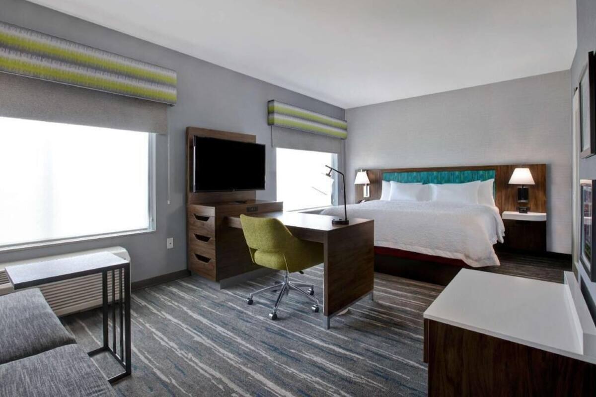 A hotel room with a bed, desk, chair, television, and bedside lamps.