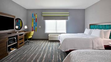 A hotel room with a large bed, a desk with a television, a chair, and a window with a view.