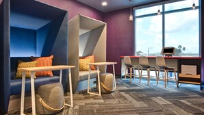 A modern office space with a blue sofa, a small table, and two chairs. - Tru By Hilton St. Petersburg Downtown Central Ave, FL (St. Petersburg)