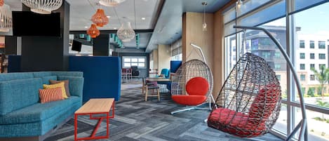 Un área de descanso moderna con un sofá azul, un sillón rojo y lámparas colgantes.