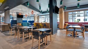 A modern indoor space with tables and chairs, large windows, and a variety of seating areas. - Tru By Hilton St. Petersburg Downtown Central Ave, FL (St. Petersburg)