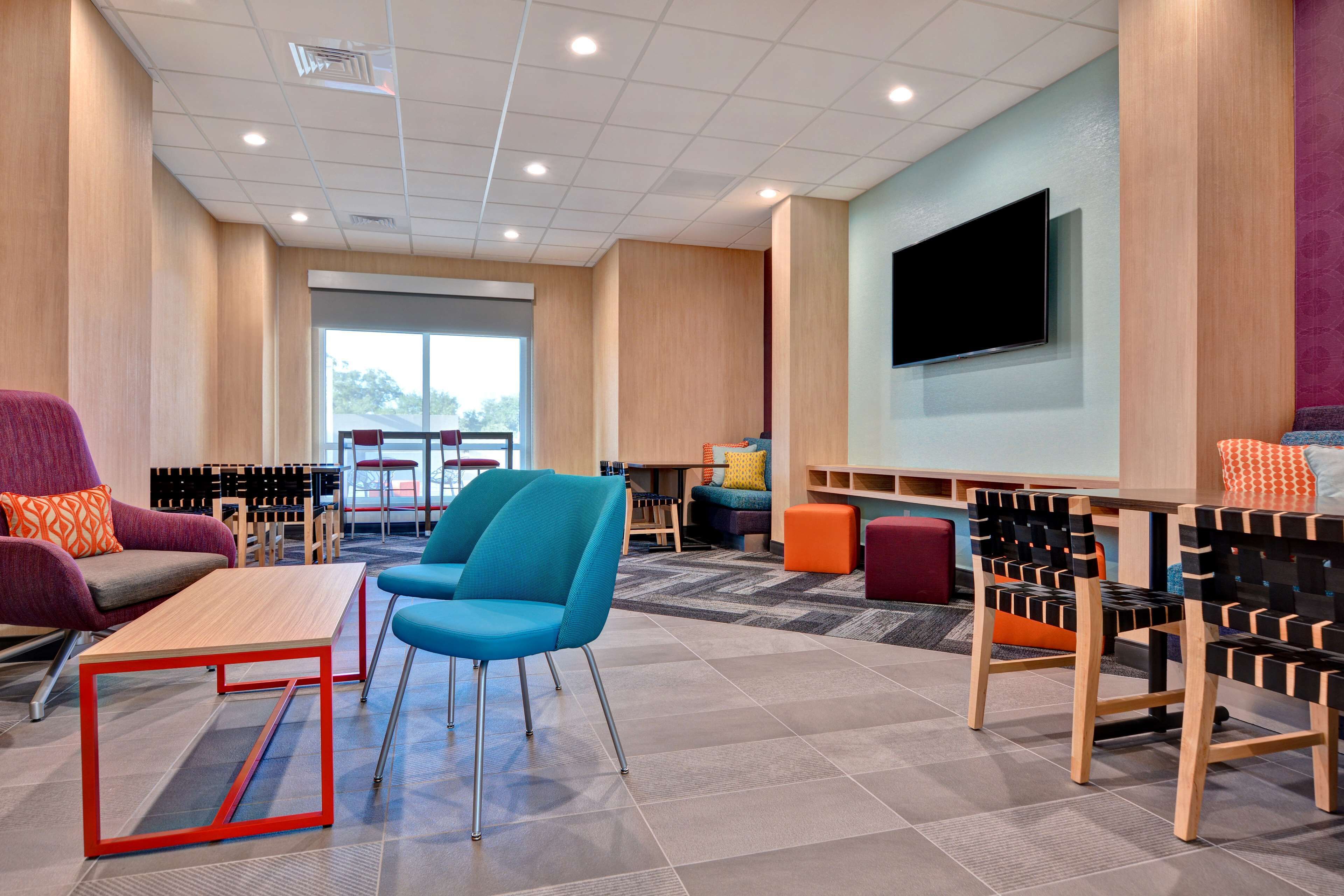 A modern lounge area with seating, a flat-screen TV, and a large window.