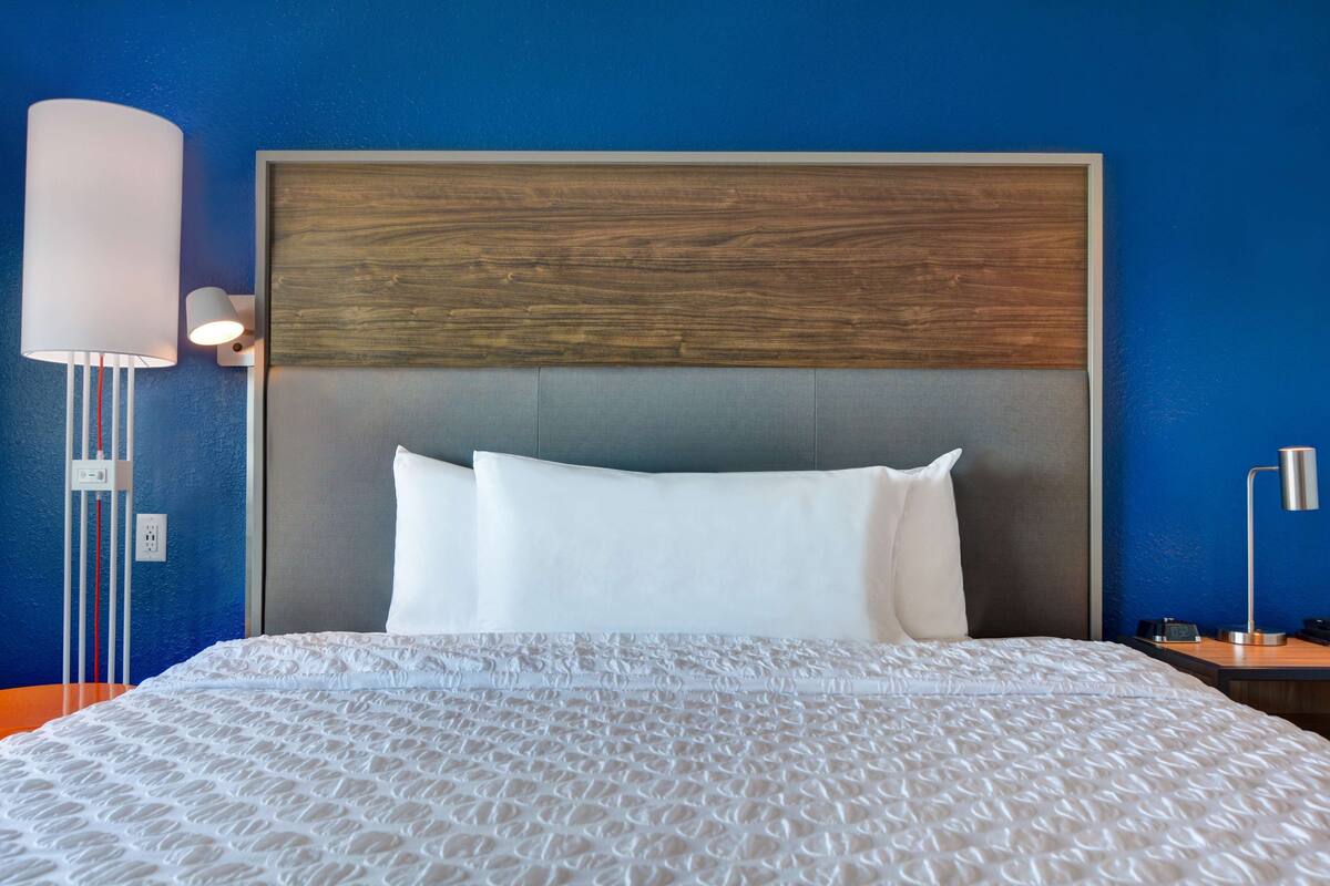 Ein Hotelzimmer mit einem großen Bett, einem Holzkopfstück und einem Nachttisch mit einer Lampe.