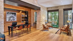 Een modern interieur met een houten eettafel, stoelen, een boekenkast en een groot raam met uitzicht op groen.
